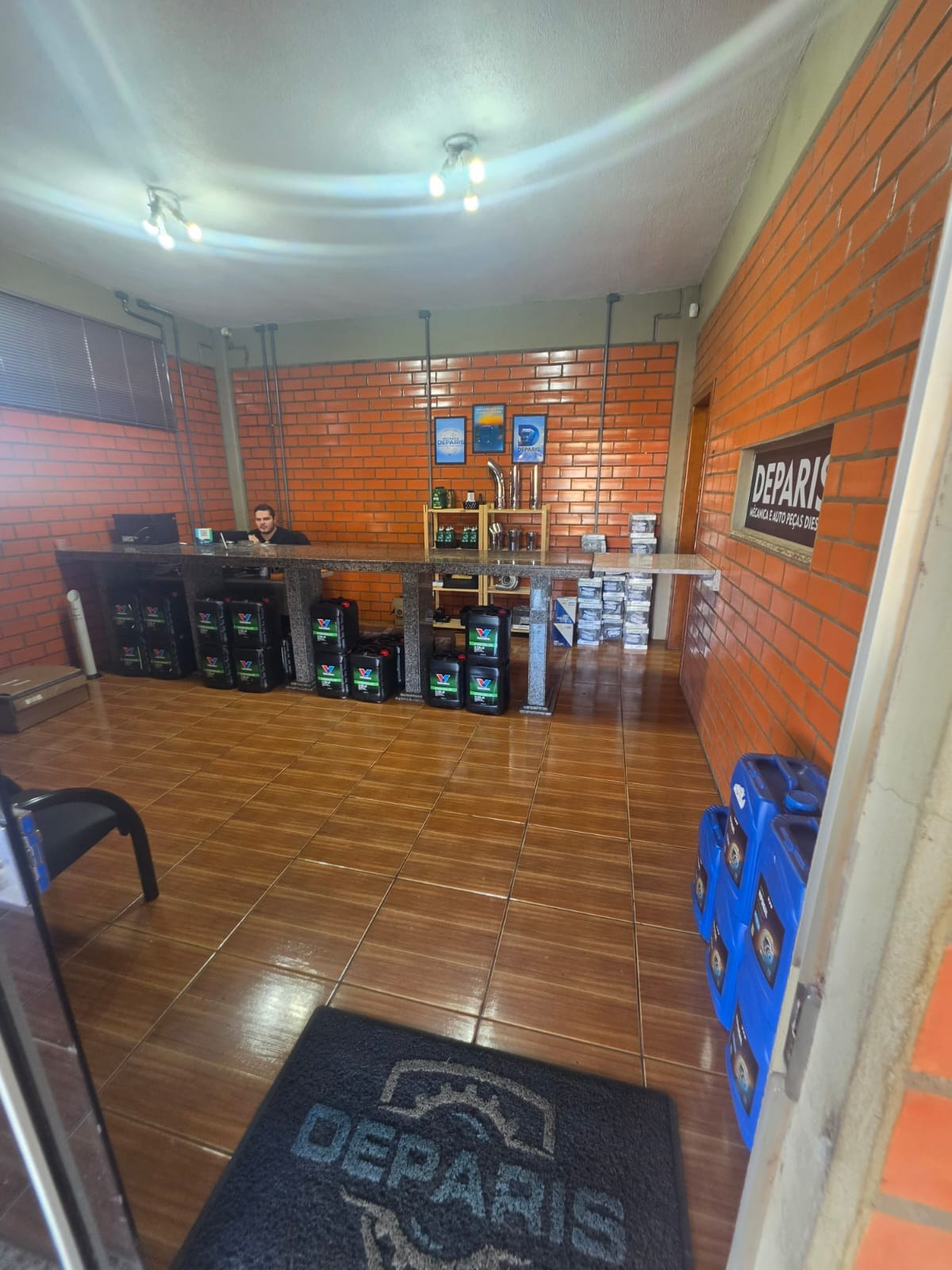 Recepção da Mecânica Deparis — balcão de peças com placa Deparis na parede
